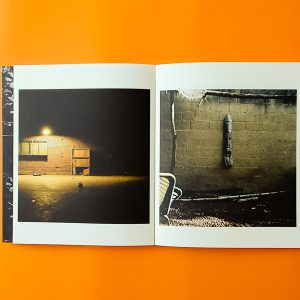 livre ouvert avec fond orange dessous , et sur une page une maison et une lumeire et sur l'autre page un mure et devant une chaise